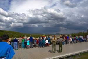 A ranger watching Old Faithful with the crowds.